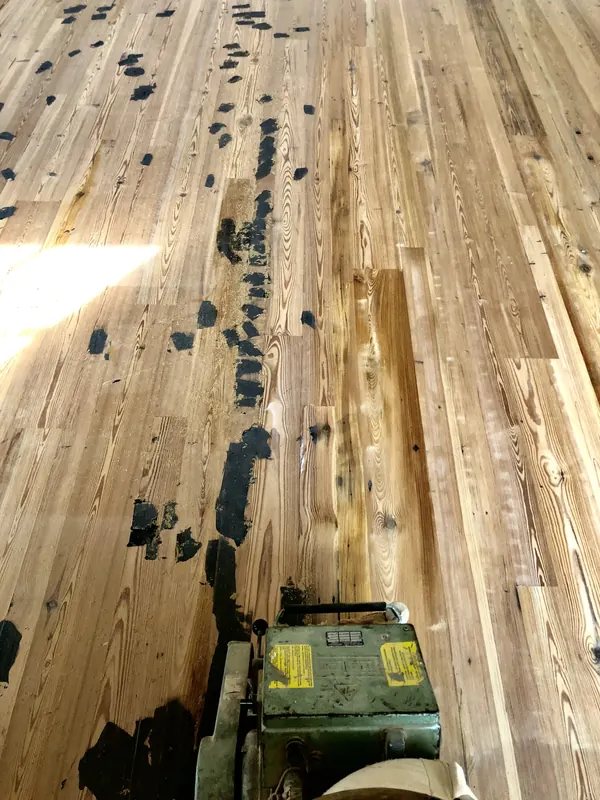 Dark patched floor with a sander alongside