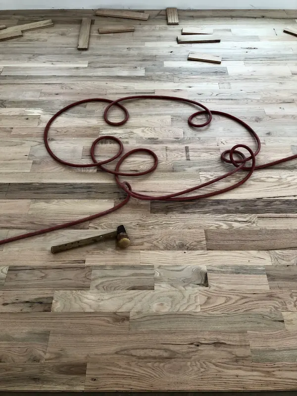 Air hose coiled on pale new boards