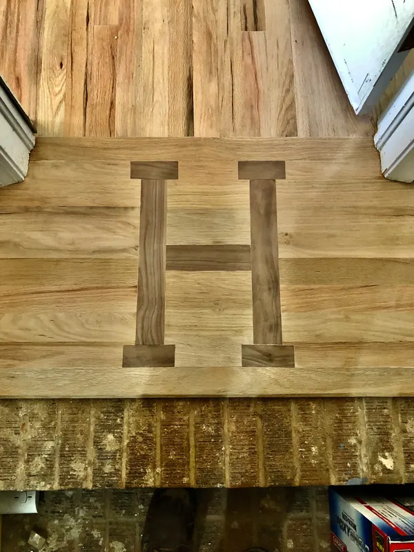 Letter H inlaid in dark wood into a pale floor